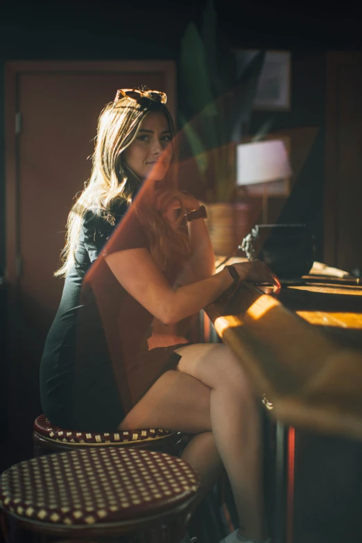 woman sitting in front of bar drinking soing out of a bottle