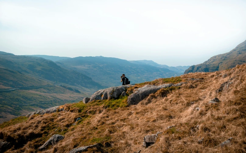 the man is sitting on top of the hill alone