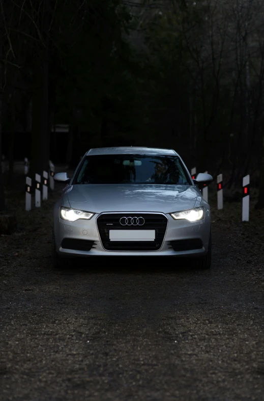 a silver car driving on a narrow road