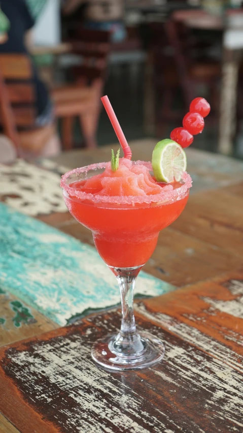 a small cocktail glass with a small drink and a slice of lime