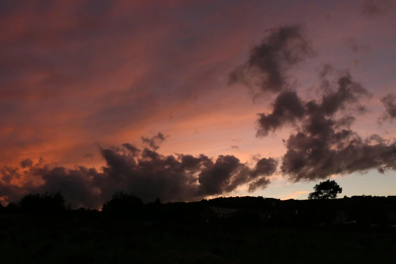 purple sky with few clouds over a hillside and grass