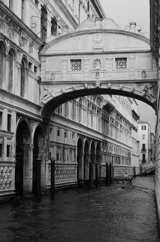 the view of a black and white street from under an arched bridge