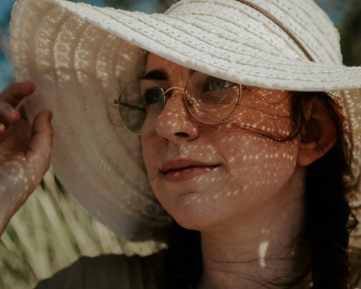 a woman in glasses is holding up her hat