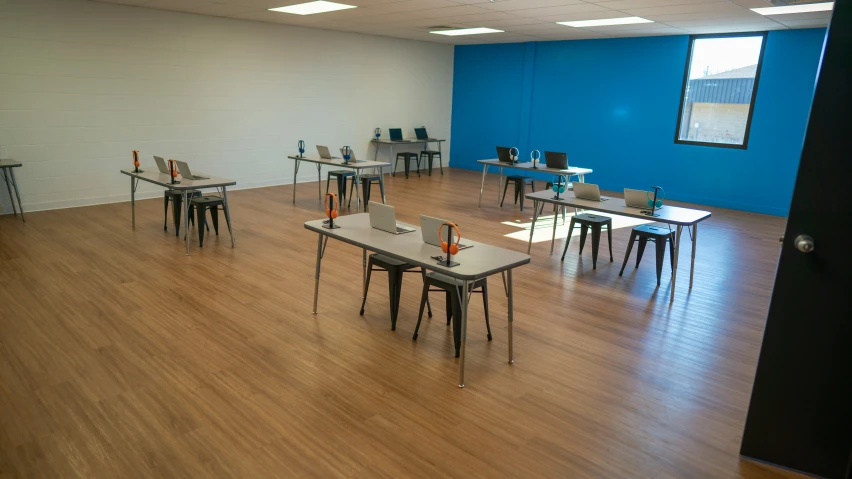 classroom with no chairs and several desks arranged around