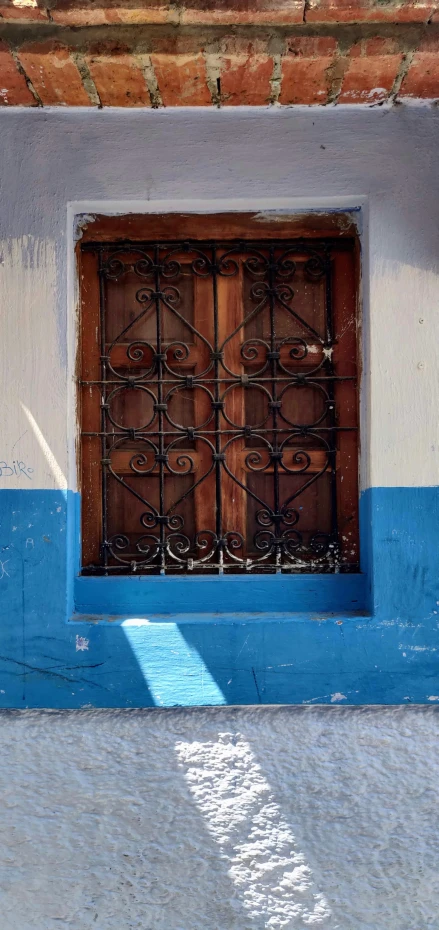 a gated window is pictured at the side of a building