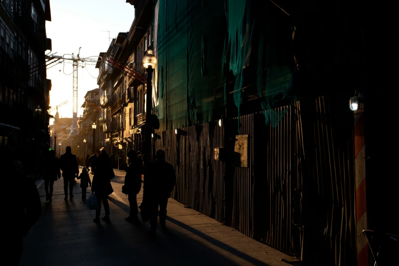 silhouettes and buildings on a street next to a fence