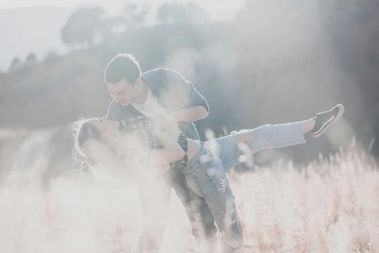 man and woman pose for the camera as they are sitting in a field