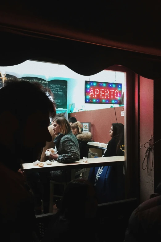 people sitting at tables in front of a bar