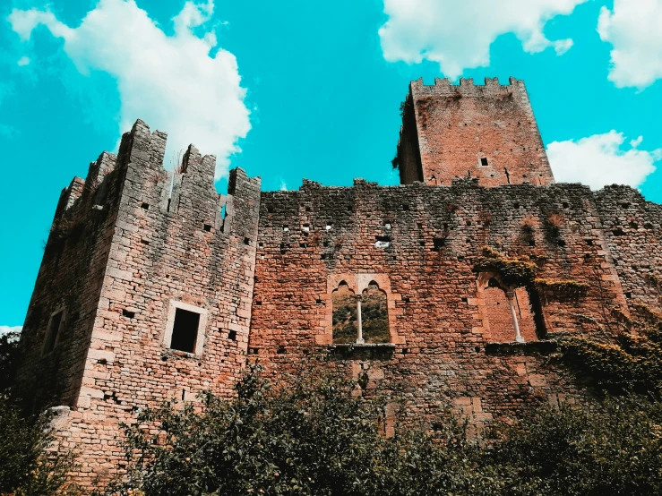 tall castle with turrets on top sitting under a cloudy blue sky