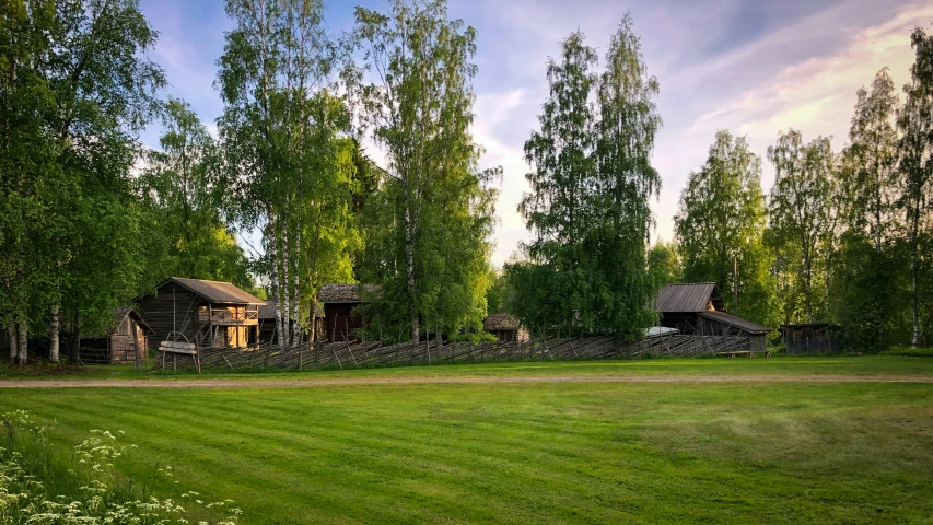 a field is shown with two cabins behind the grass