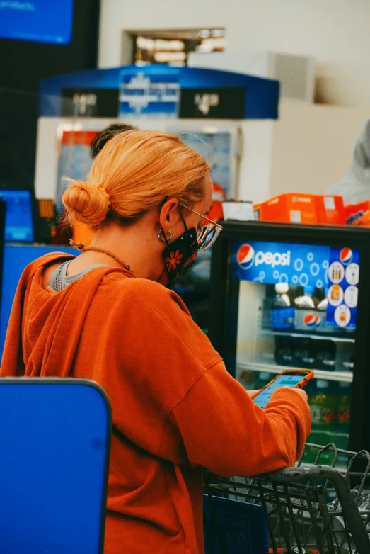 a young woman shopping at a grocery store while using her cell phone