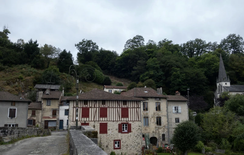 an old house with shutters on top sitting at the bottom of a cliff