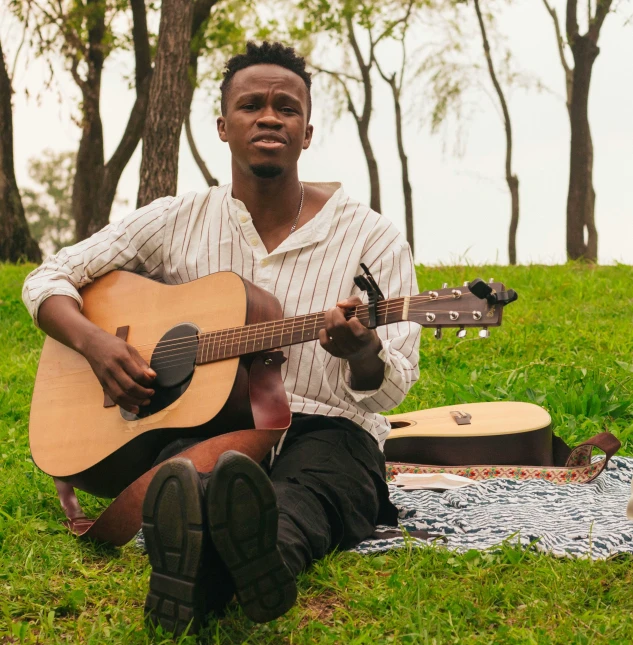 a man sitting on a blanket with his guitar