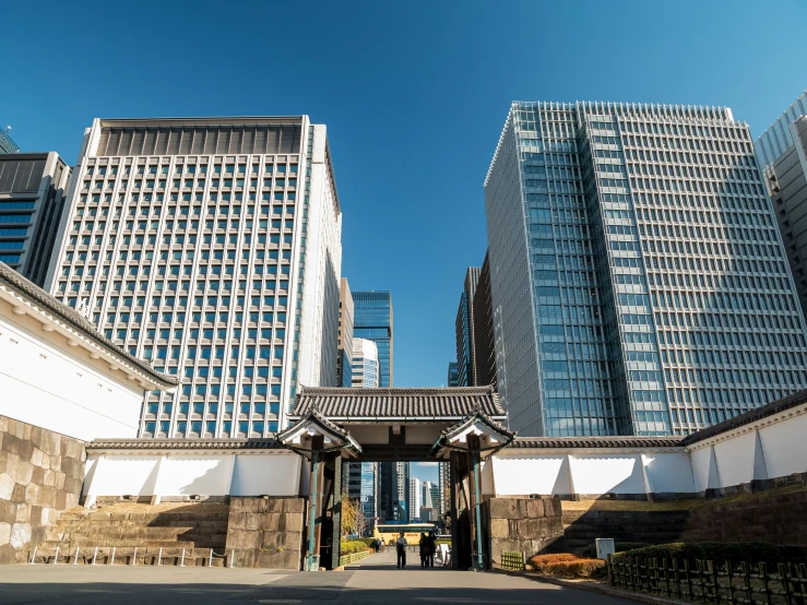 some tall buildings are behind a concrete fence