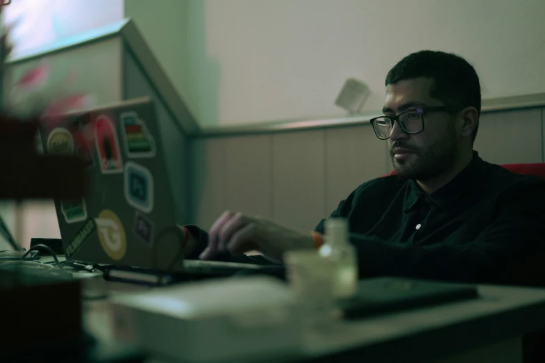 man sitting in front of a laptop while wearing glasses