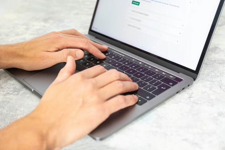 person typing on their laptop keyboard while sitting down