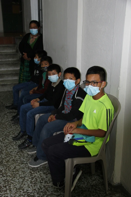 several people sitting down wearing masks on their faces