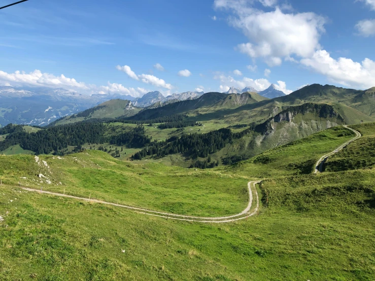 a grassy hill with many roads and mountains in the background