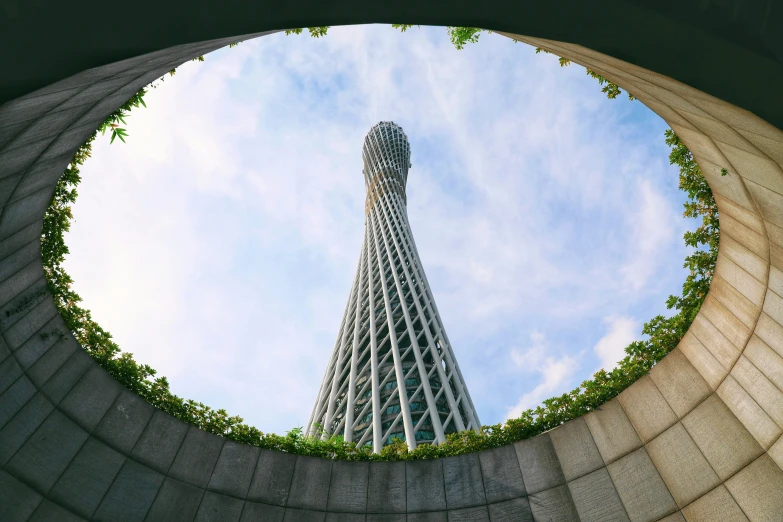 looking up at a round concrete building with a curved tower