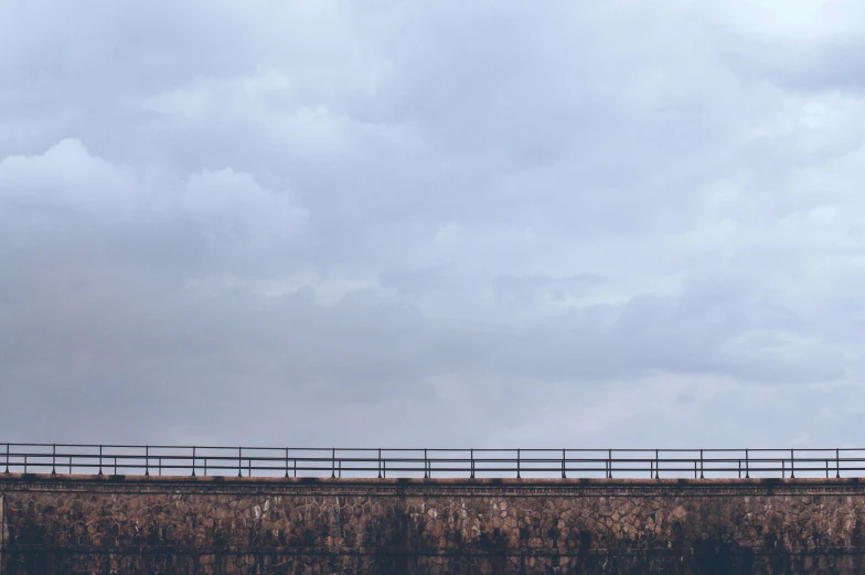 a train passing by on an overpass in front of dark clouds