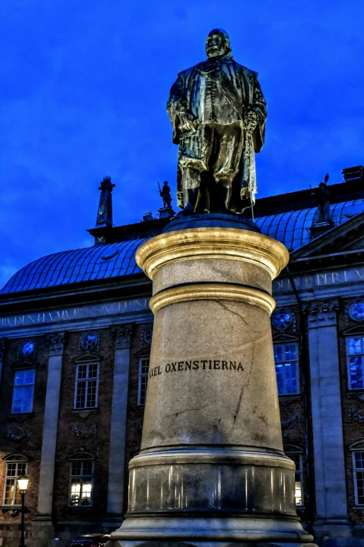 a very tall statue sitting in front of some buildings