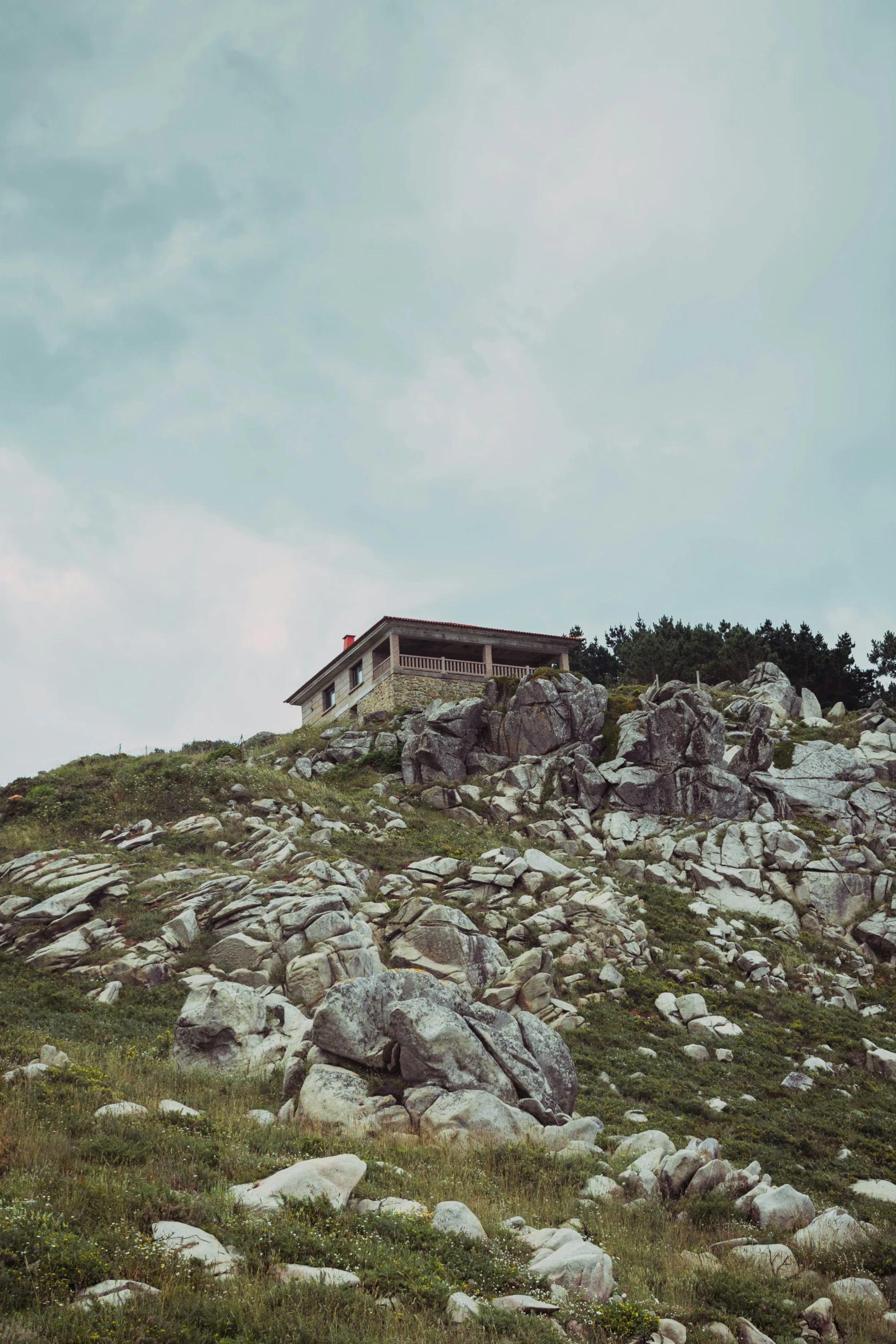 a house on top of a hill with rocks and grass