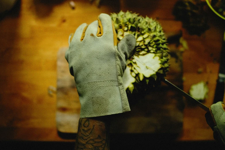 a gloved hand with a large piece of art next to a flower arrangement