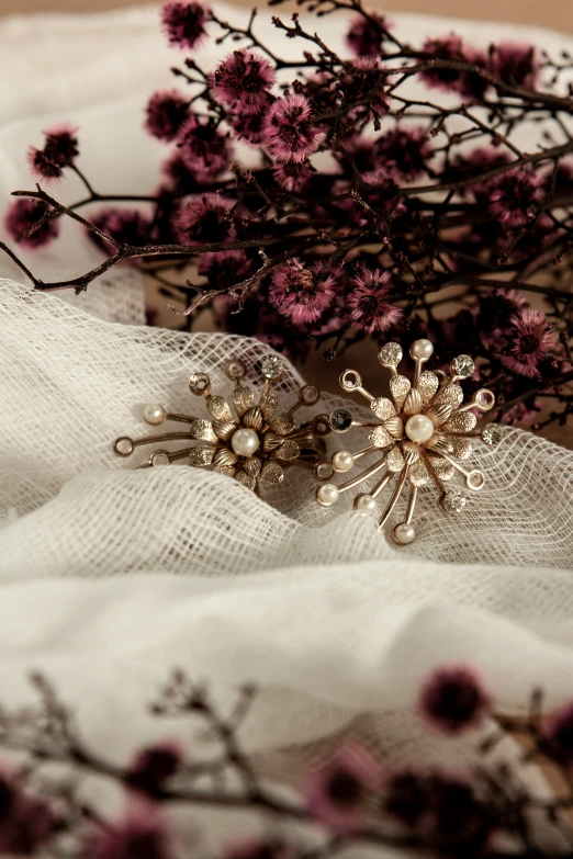 two flower brooches laying on a white cloth