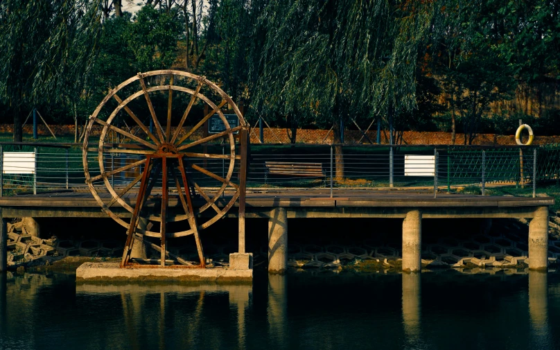 a large water wheel in the water by a dock