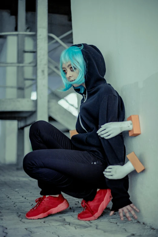 a woman with blue hair wearing sneakers and a hoodie