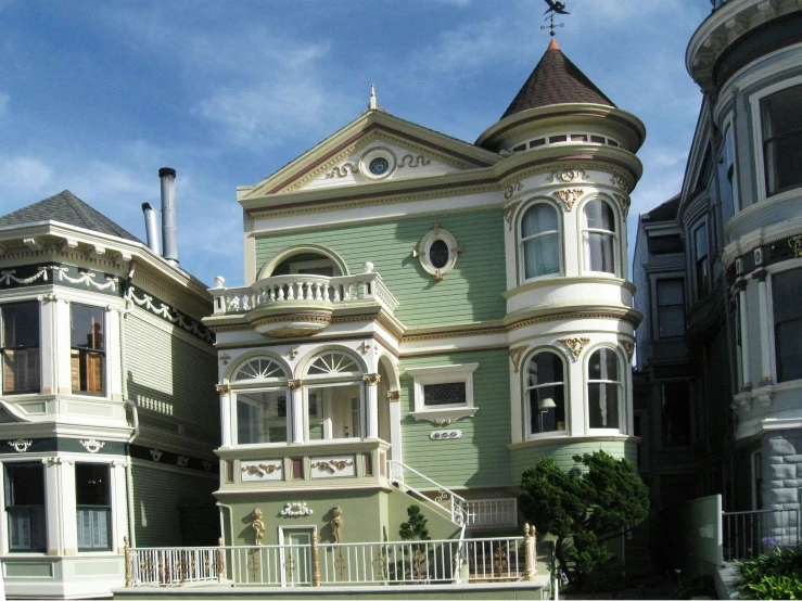 a very pretty victorian style house that looks like it is painted in green and white