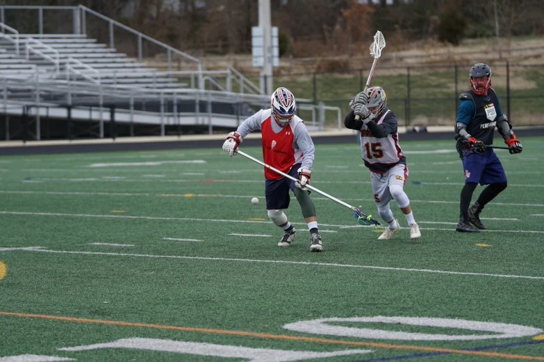 three men on an athletic field with lacrosse sticks