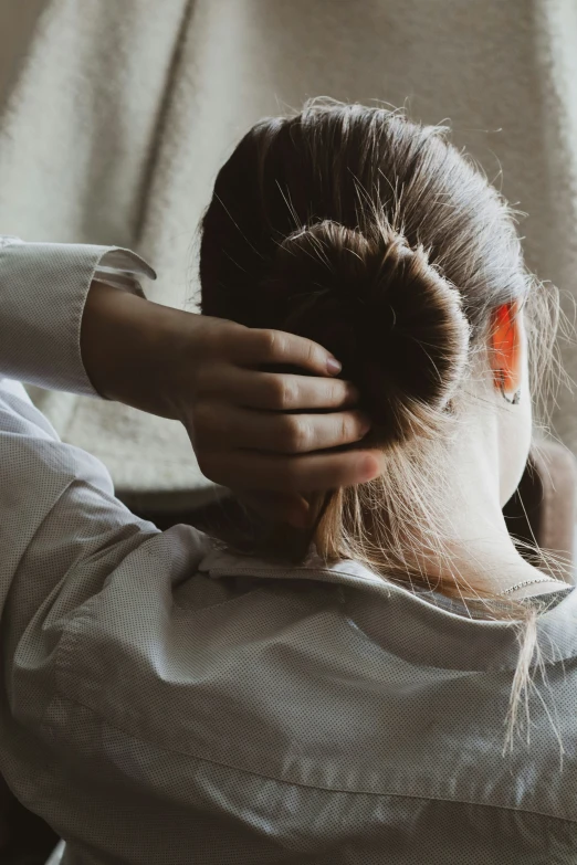 woman sitting down with hair wrapped back and a ponytail