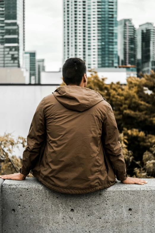 a man sits at the edge of a wall overlooking a city