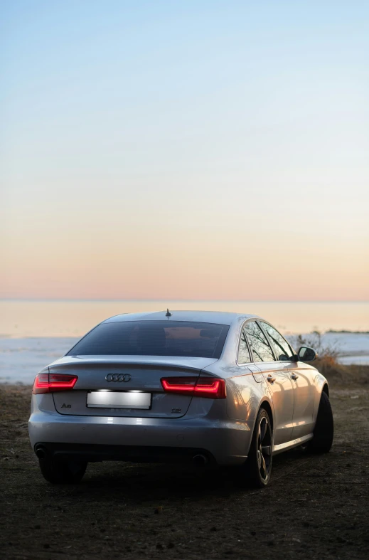 a silver car parked near water on a beach