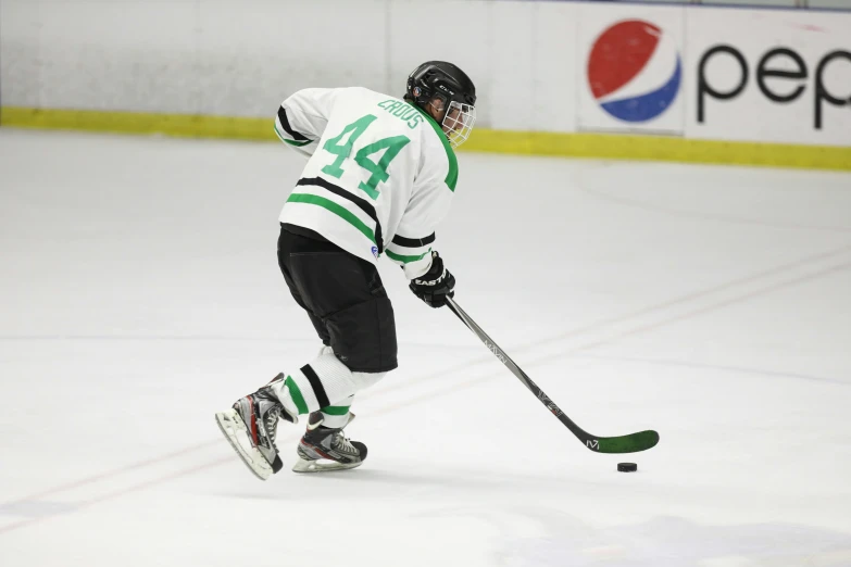 a hockey player wearing green and white uniform on the ice