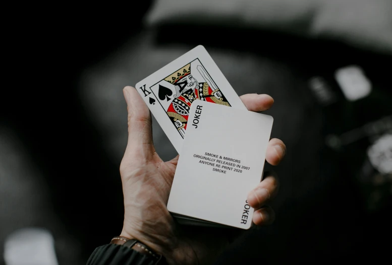 person holding a playing card in their left hand