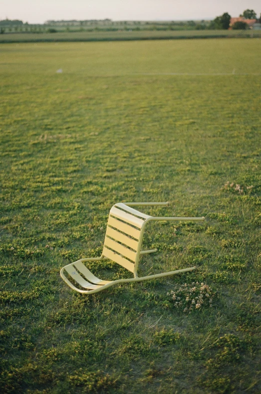 a yellow bench on a grassy field