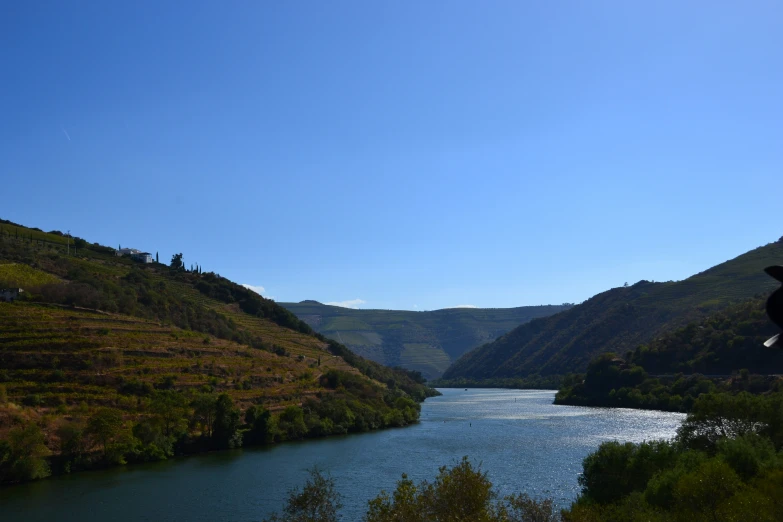 a body of water sitting next to green hills and trees