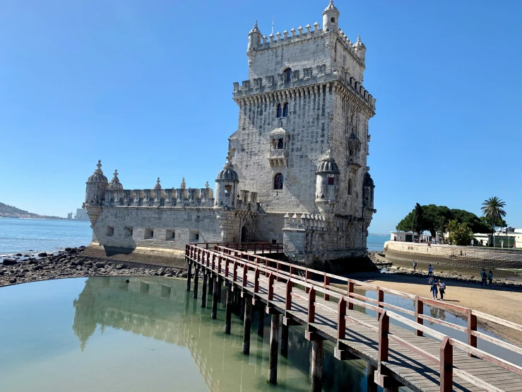 a large stone tower on the shore near water