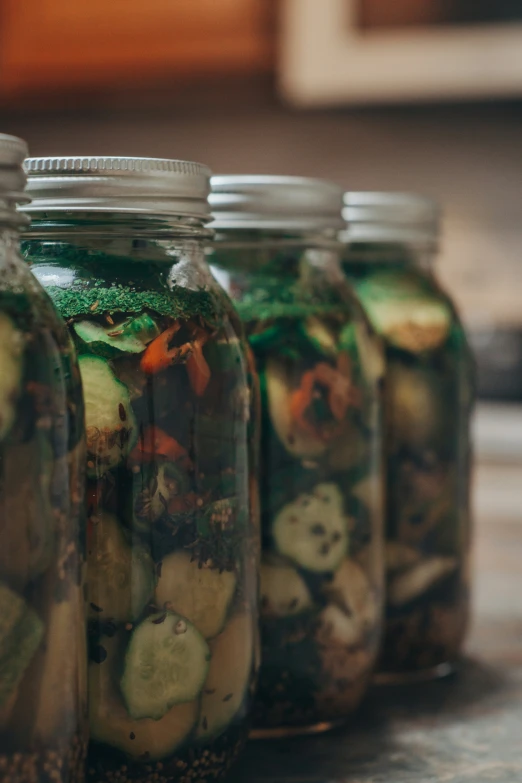 a close up of four jars with pickles in it