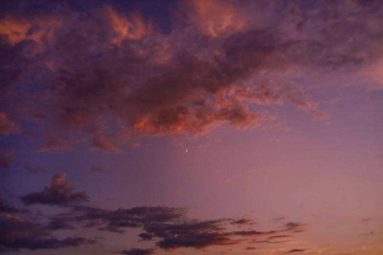 a beautiful sky with clouds and the moon just after sunrise