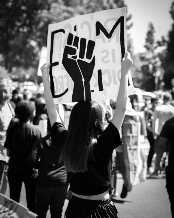 girl protesting in the street holding a sign that says march against racism