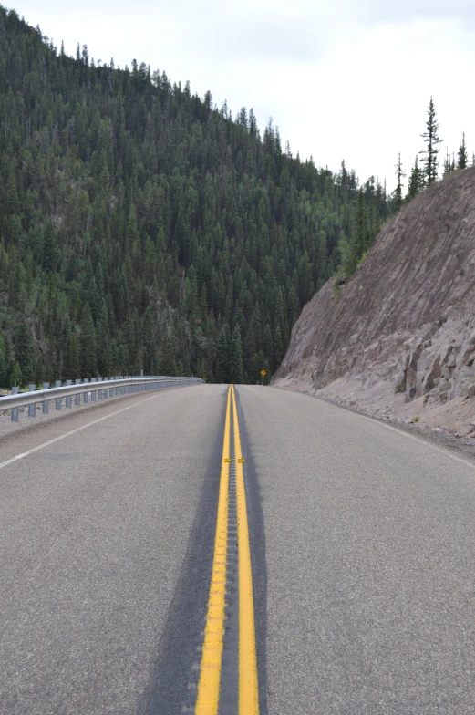 an empty road with one lane down next to a hill