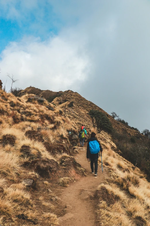 two people walking up a hill on hiking gear