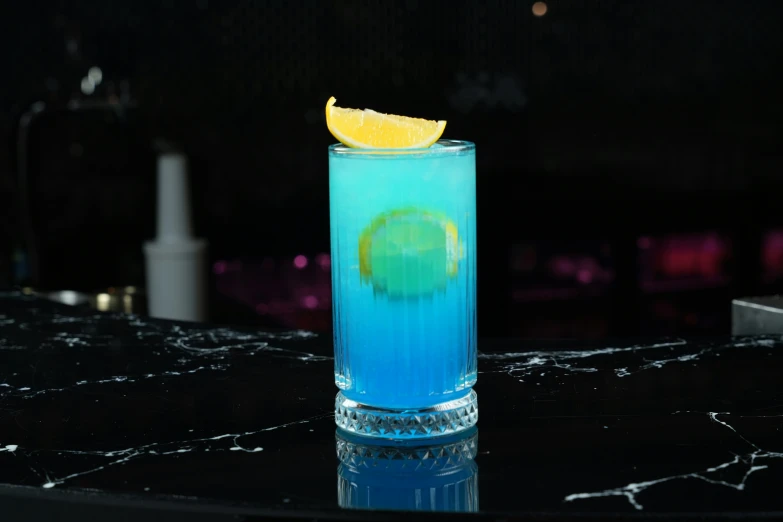 a blue cocktail with lemon garnish on the edge