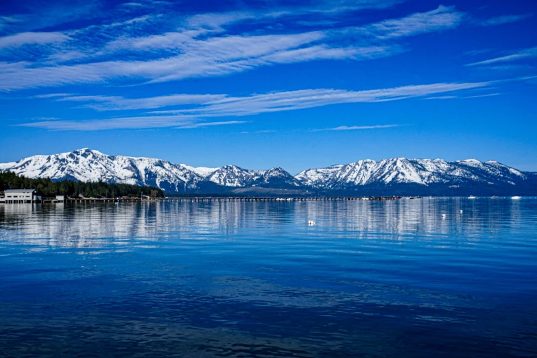 the mountains are reflecting off of the blue water