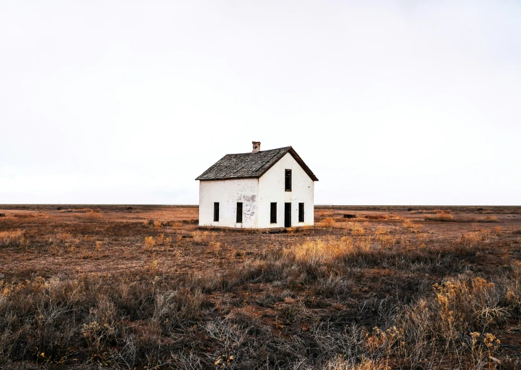 this abandoned white house sits alone in the middle of a field