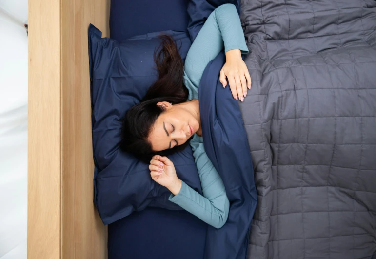 a woman is sleeping on her bed with her hands under the pillow