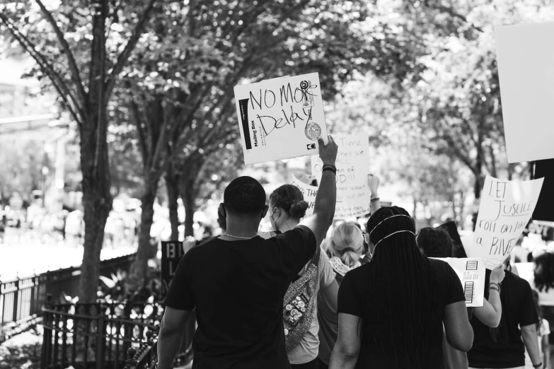 a group of people holding up signs and pointing to trees